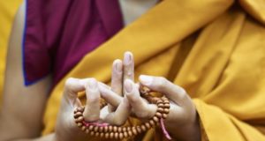 Una monaca buddista tibetana esegue il Mandala Mudra con il suo mala (perline di preghiera buddista). Foto per gentile concessione di Olivier Adam